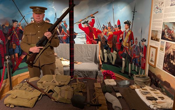 photo of man in WW1 uniform with a table full of military equipment.